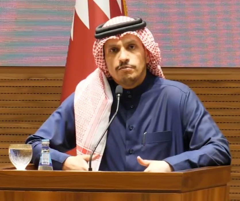 Man in traditional Middle Eastern attire speaking at a podium.