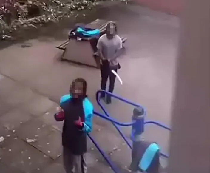 Prisoners brandishing knives in a prison yard.