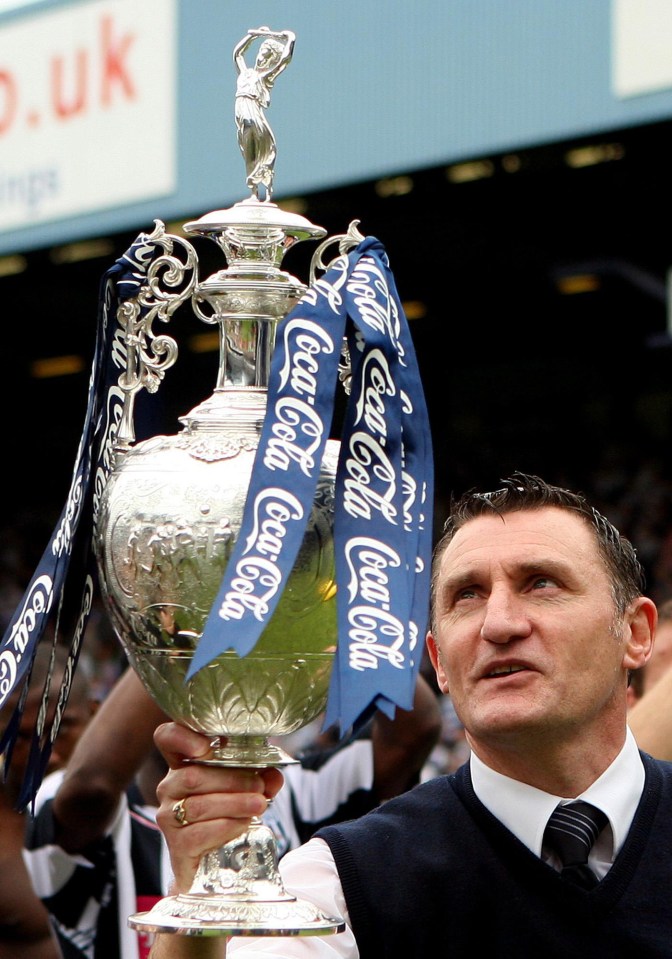 A manager holding a Coca-Cola Championship trophy.