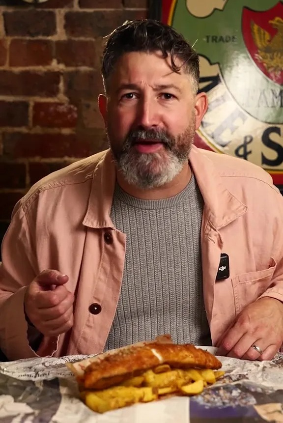 Man gesturing towards fish and chips.