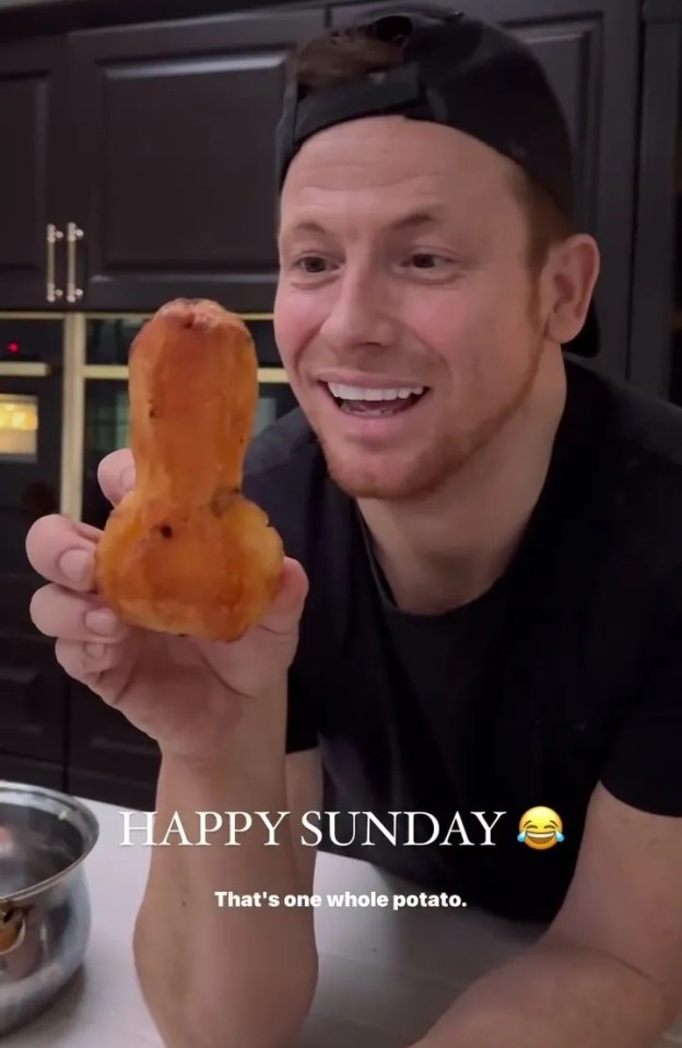 Man holding up a roasted potato shaped like a penis.