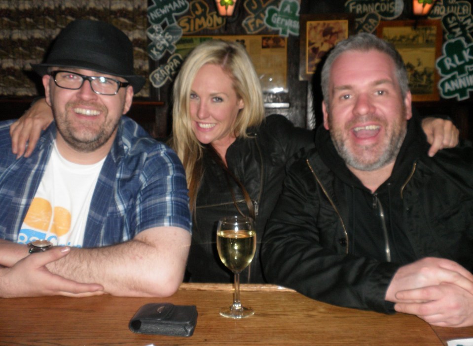 Three people sitting at a bar; a woman is between two men.