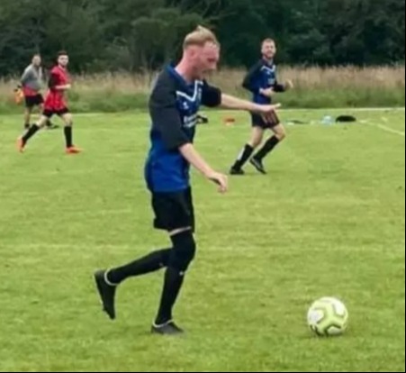 Soccer player kicking a ball on a field.