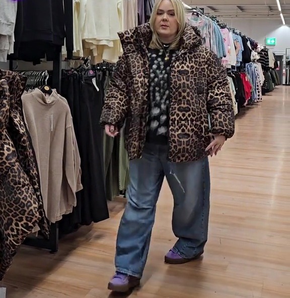 Woman in leopard-print jacket in clothing store.