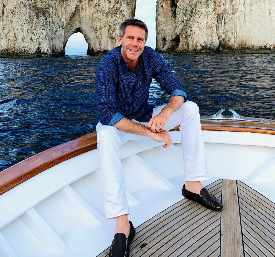 Man sitting on a boat in front of Faraglioni rocks.