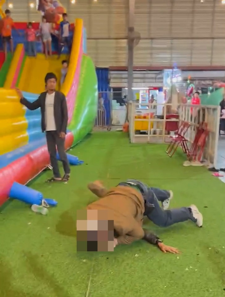 Two men fighting on the ground at a market.