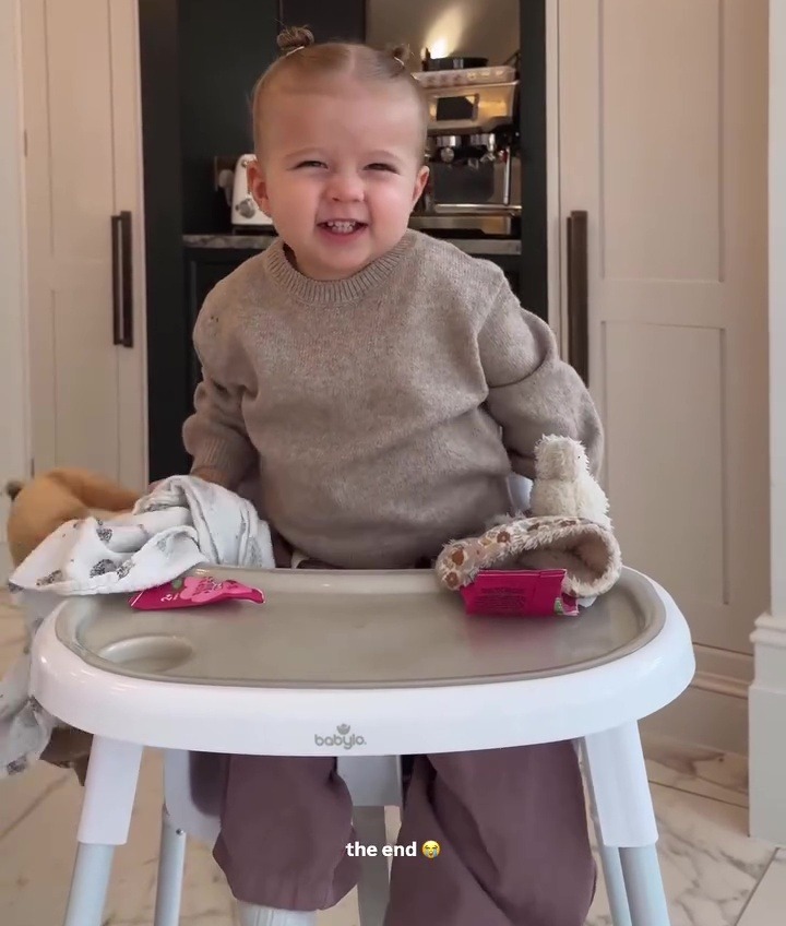 Smiling toddler sitting in high chair.