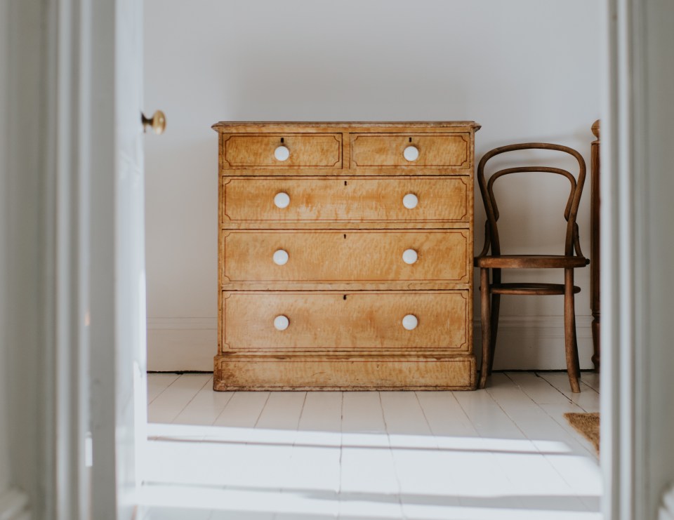 Wooden dresser and chair in a bright bedroom.