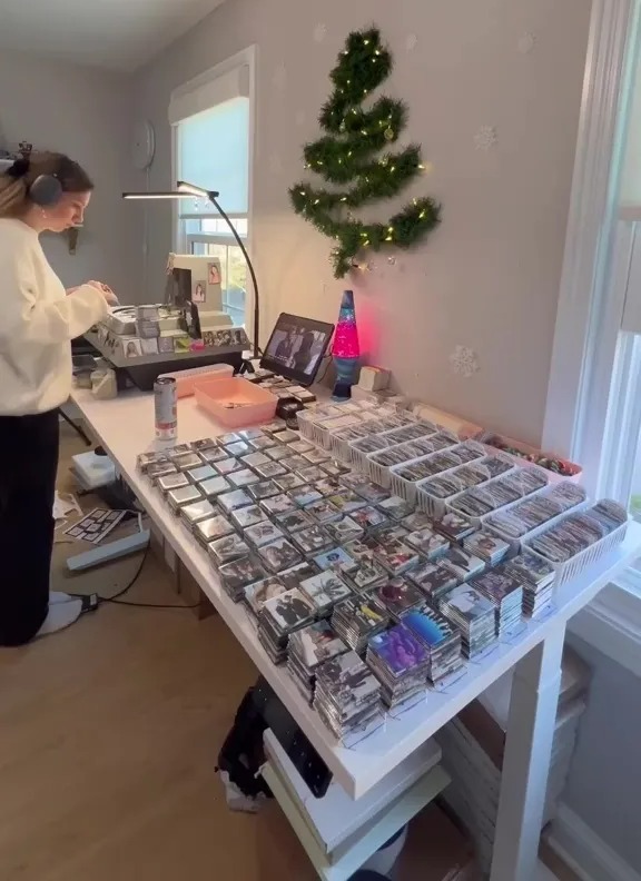 Person working at a table covered in stacks of fridge magnets.