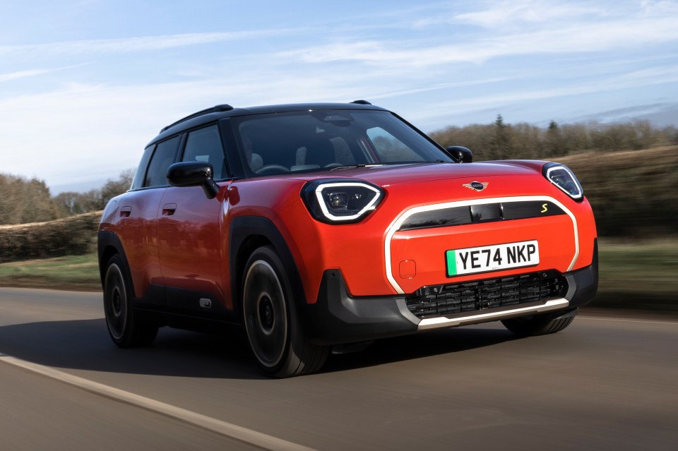 Red Mini Cooper driving on a road.