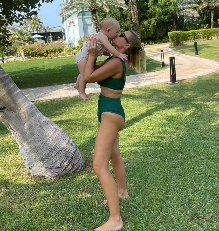 a woman in a green bikini holds a baby in her arms