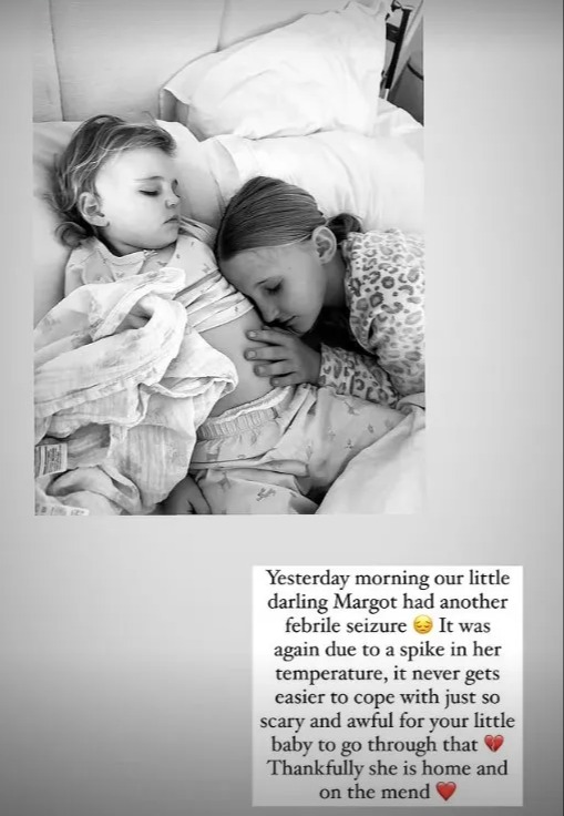 Black and white photo of two young girls sleeping in bed; one is cuddling the other.