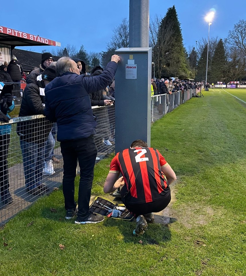 A football player fixing a floodlight at a stadium.