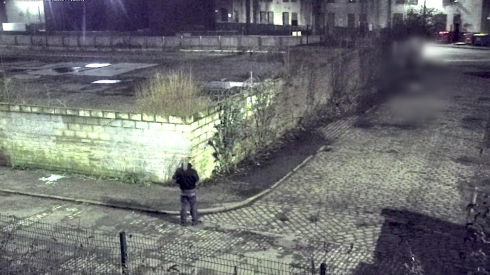 CCTV image of a man standing on a street at night.