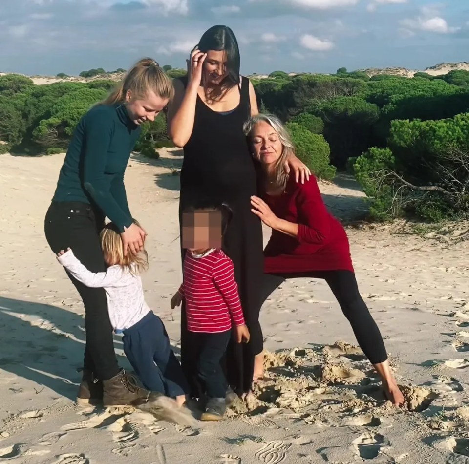 A pregnant woman with her boyfriend's wife, another girlfriend, and their two children on a beach.