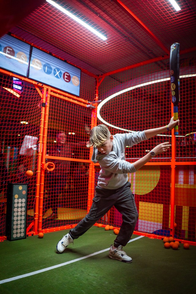 Boy swinging bat in an indoor batting cage.