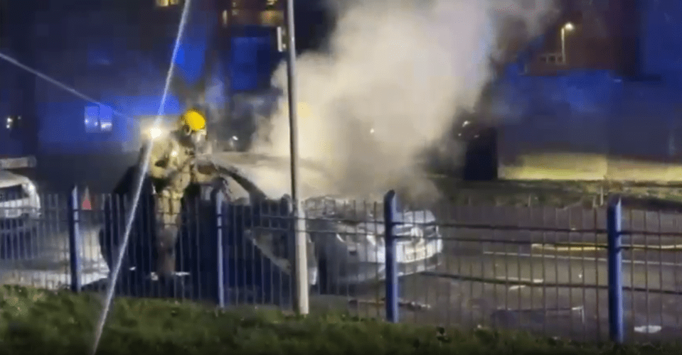 Firefighter extinguishing a burning car.