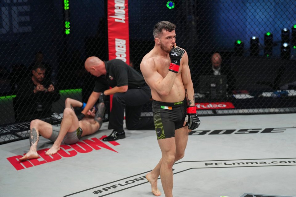 A mixed martial arts fighter raises his hand in victory after a match.