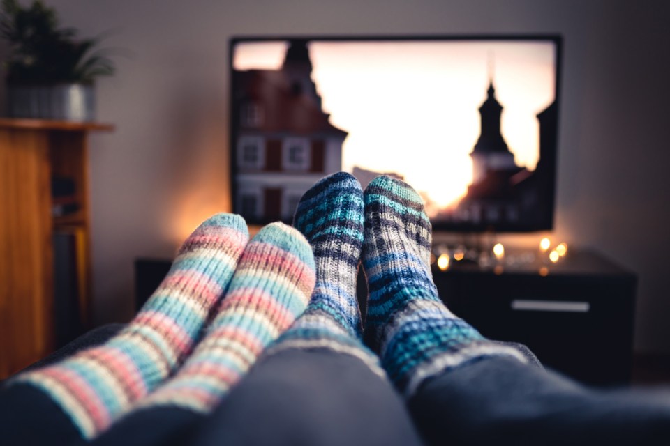 Couple's feet in warm socks watching TV.