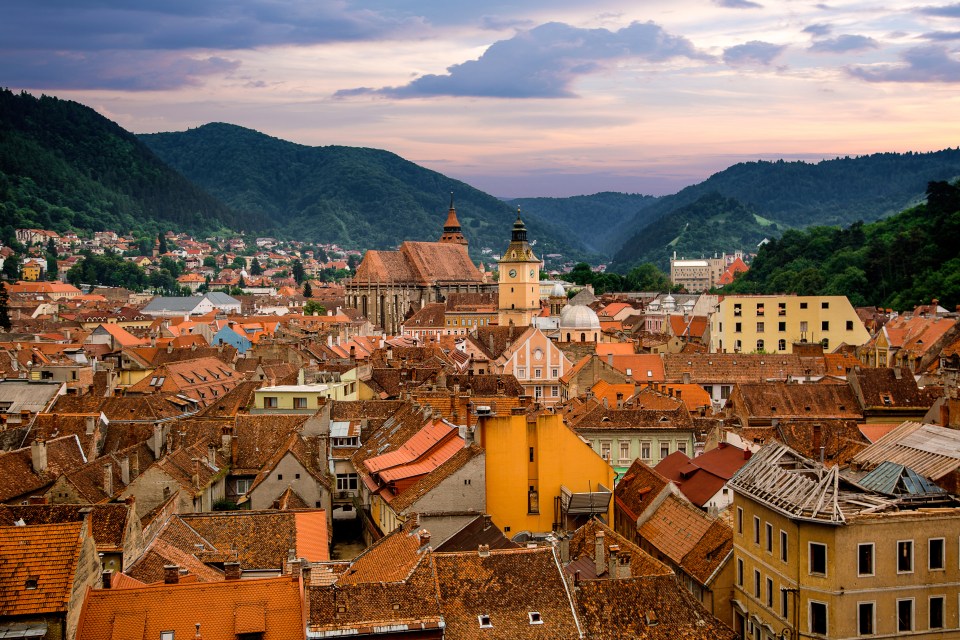 Brasov, Romania cityscape at sunset, with Tampa Mountains in the background.