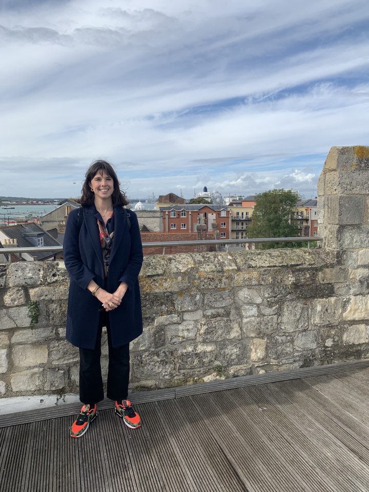 Woman standing on a stone wall overlooking a city.