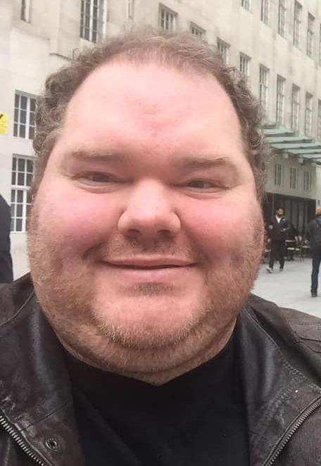 Close-up photo of a smiling man.