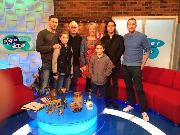 Group photo of eight people on a TV set.