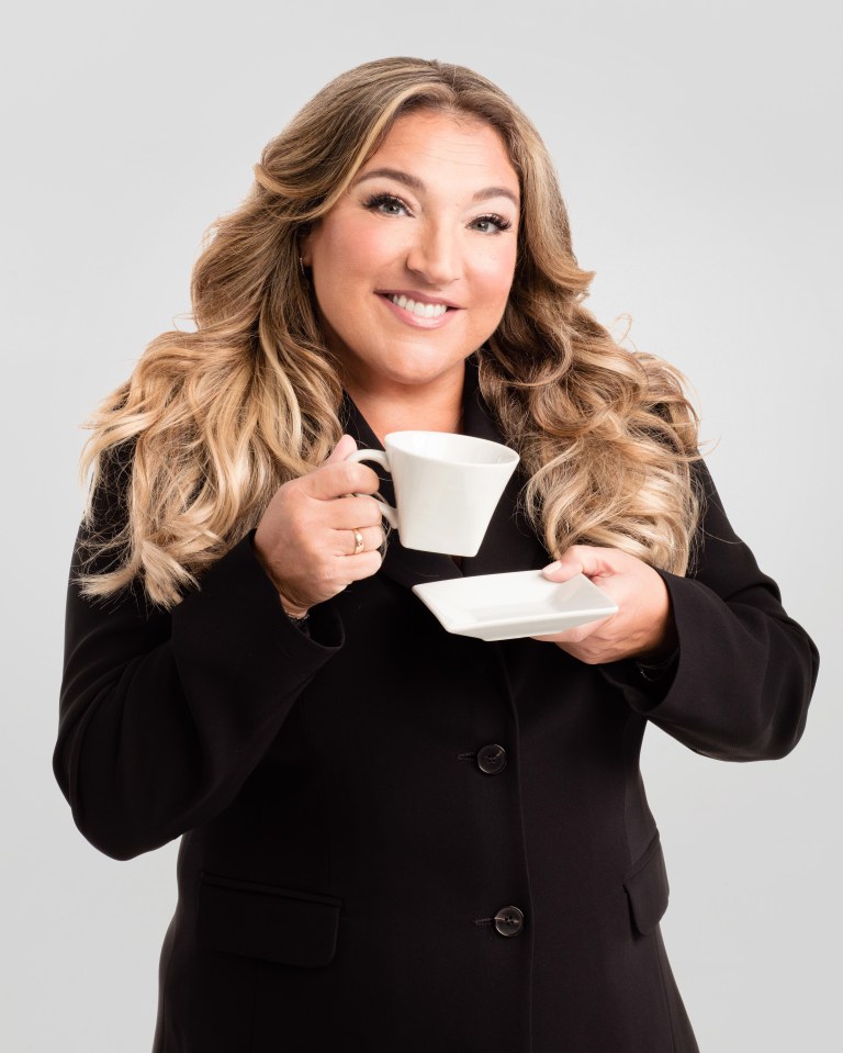 Woman in a black blazer holding a teacup and saucer.