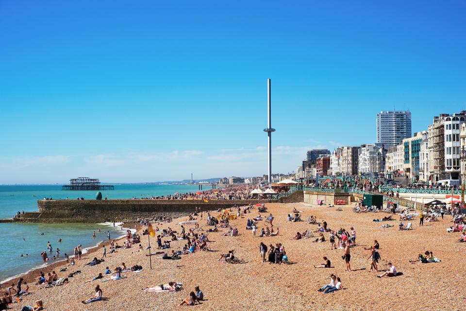 Crowded Brighton beach with the British Airways i360 in the background.