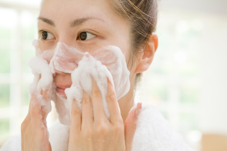 Woman washing her face with cleanser.