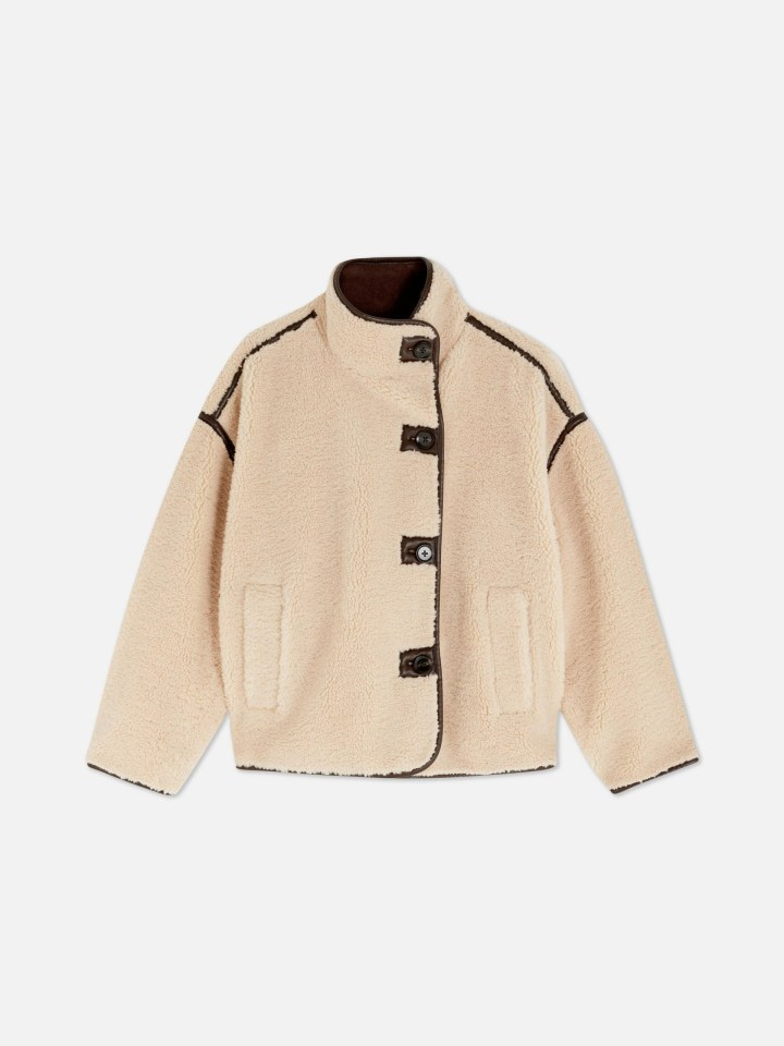 Beige teddy jacket with brown trim and buttons.