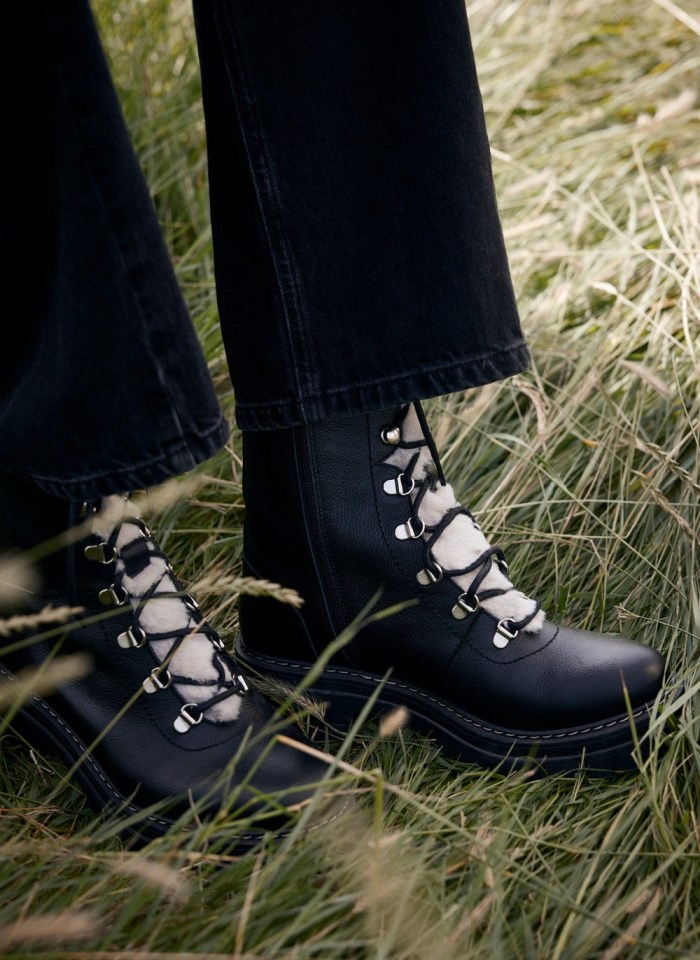 Black leather boots with cream laces in the grass.