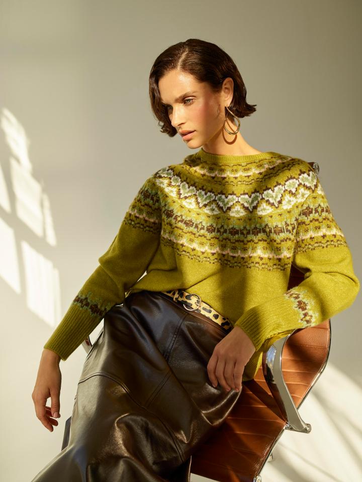 Woman in green Fair Isle sweater and brown leather skirt.