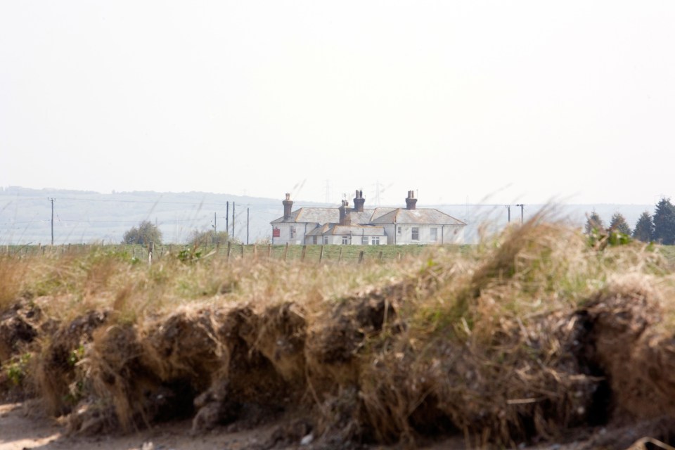 A house viewed from behind a grassy dune.