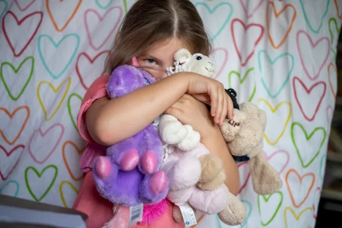 Girl hugging stuffed animals.