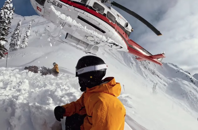 Helicopter landing in snowy mountains near a skier.