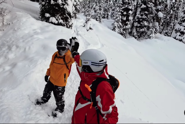 Two skiers giving each other a high five on a snowy mountainside.