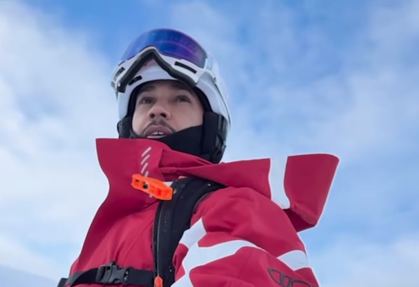 Man in ski gear looking up at the sky.