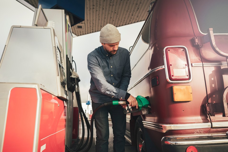 Man refueling a vintage van at a gas station.