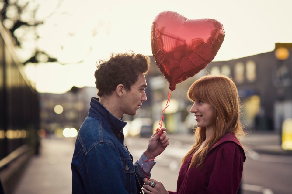 Young couple sharing a heart-shaped balloon.