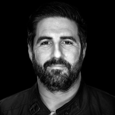 Black and white headshot of a man with a beard.