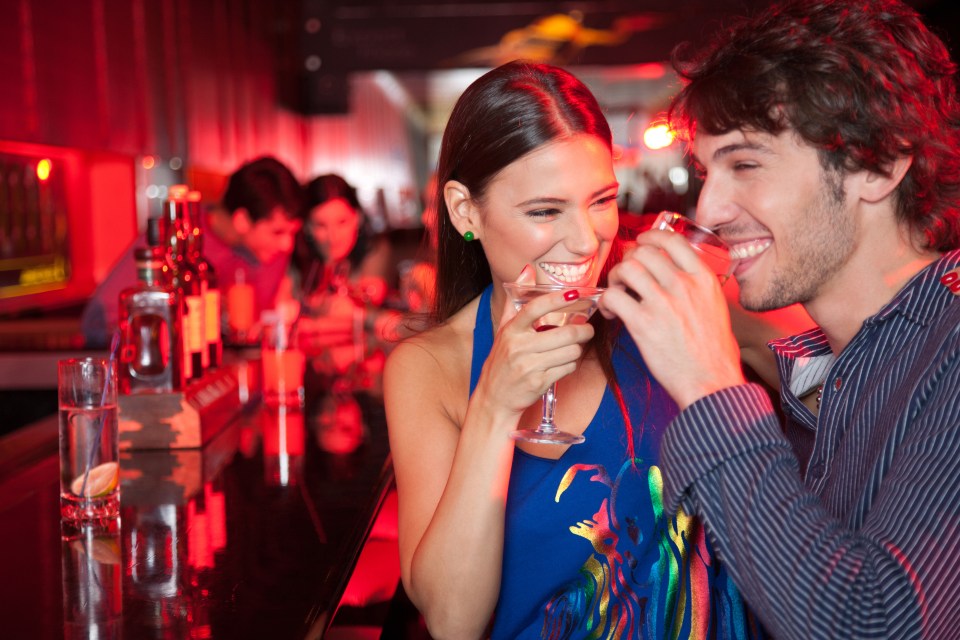 Young couple enjoying cocktails at a bar.