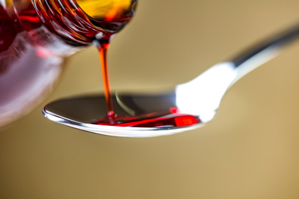 Red liquid pouring from a bottle into a spoon.