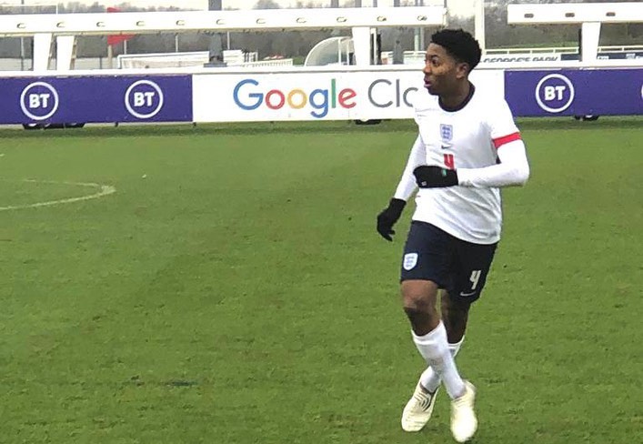 Soccer player in England uniform jogging on a field.