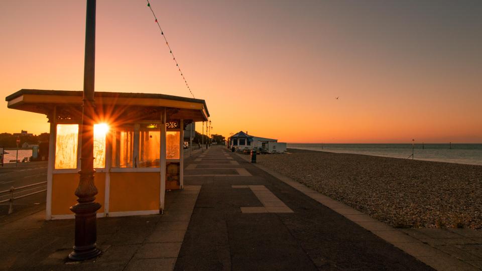 Sunrise over Southsea esplanade with Victorian beach shelters.