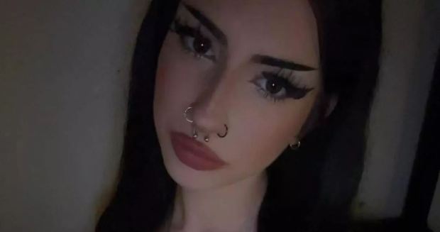 Close-up of a person with dark hair and makeup, wearing a septum piercing.