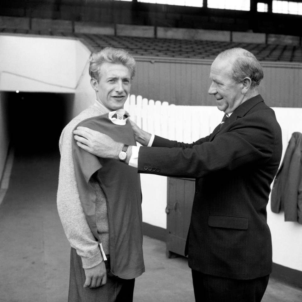 Manchester United manager Matt Busby (r) holds a United shirt against his new signing, Denis Law (l), who cost £115,000 from Torino