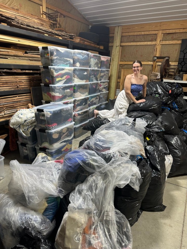 Woman surrounded by bags and bins of clothing she resells online.