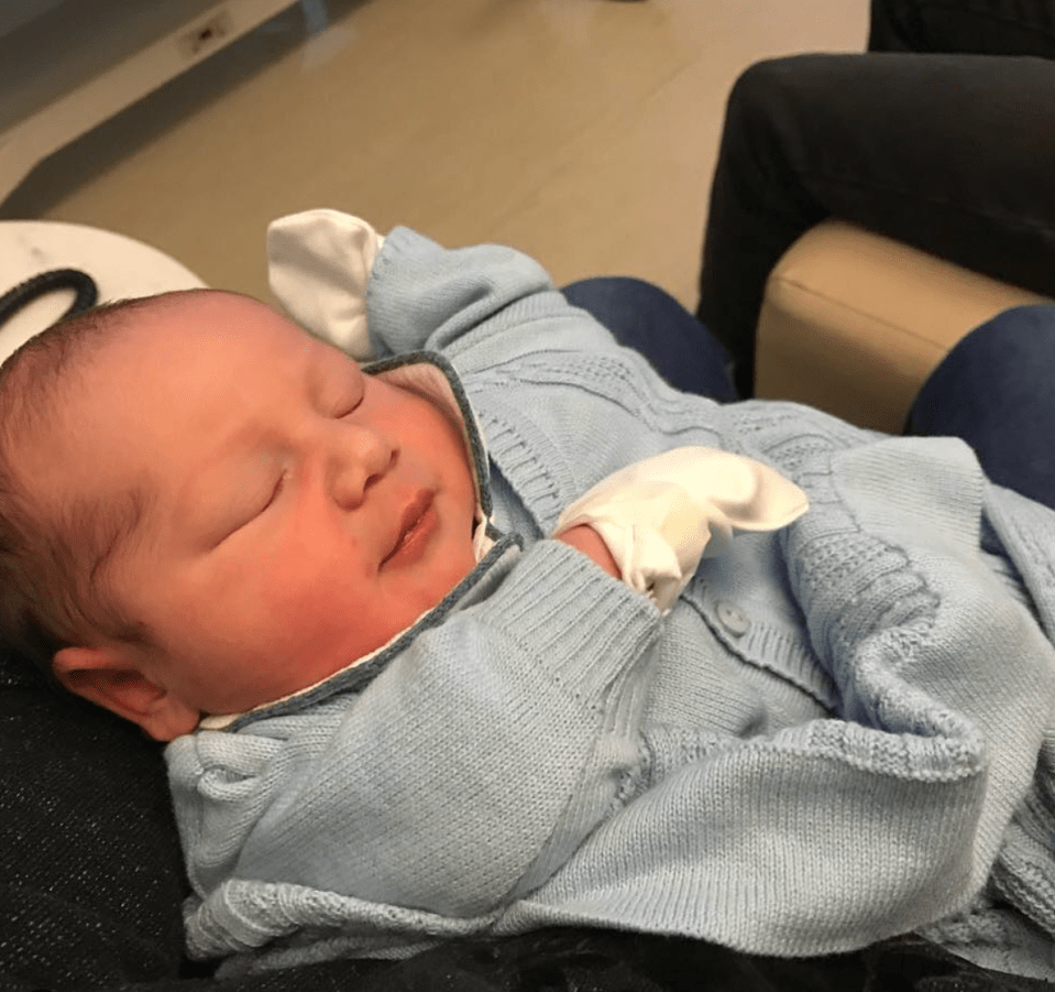 Newborn baby sleeping in a light blue cardigan.