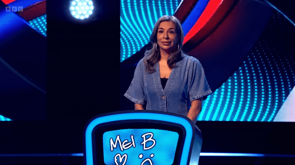 Mel B standing behind a game show podium.